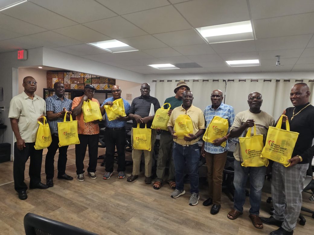 Eleven community members standing together, each holding a bag of supplies distributed in partnership with the Children's Services Council of Palm Beach County.