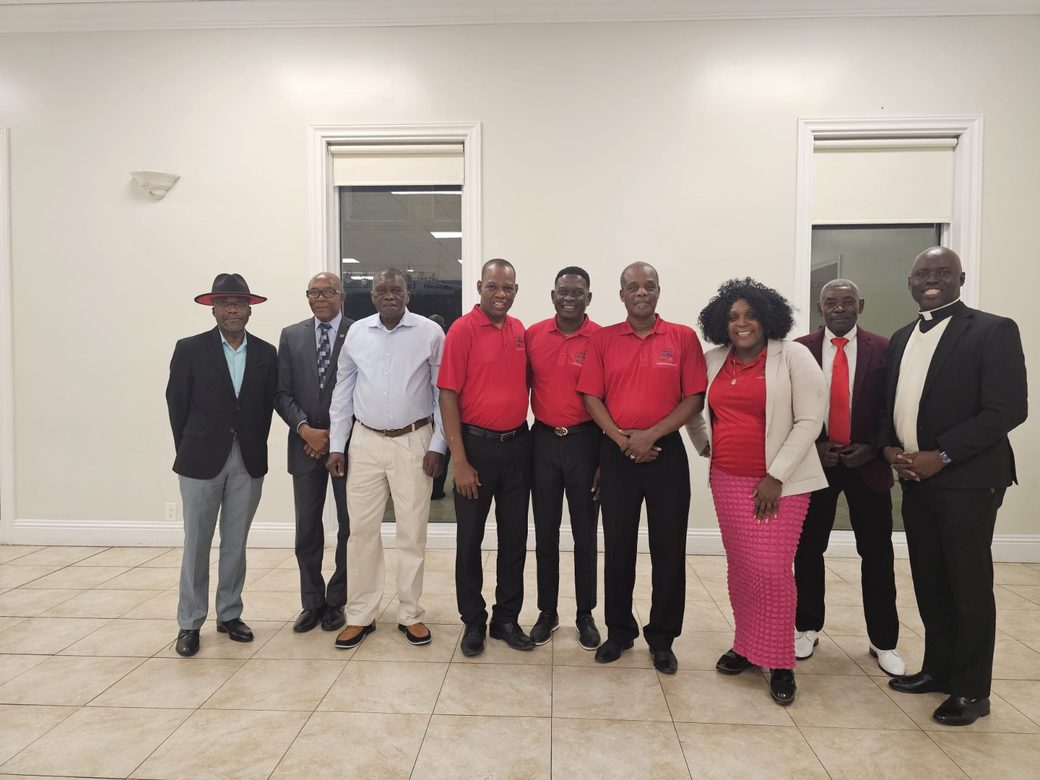 Nine HTHH volunteers and leaders standing together, several wearing the organization's red branded shirts.